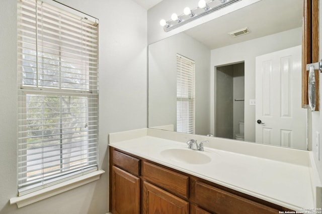 bathroom with toilet, a wealth of natural light, vanity, and visible vents