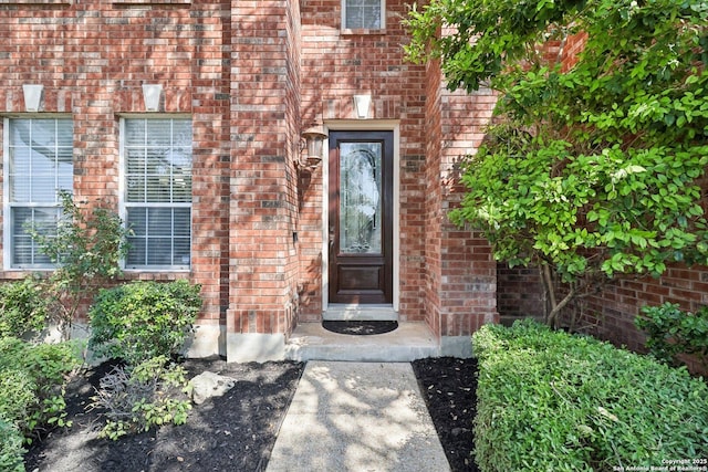 view of exterior entry featuring brick siding