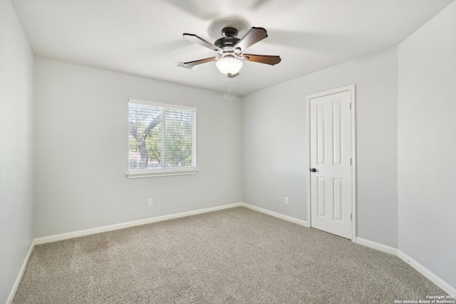 carpeted spare room with ceiling fan and baseboards