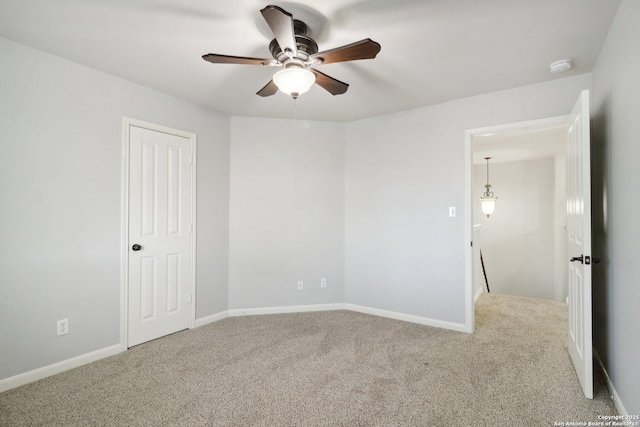 carpeted spare room with baseboards and a ceiling fan