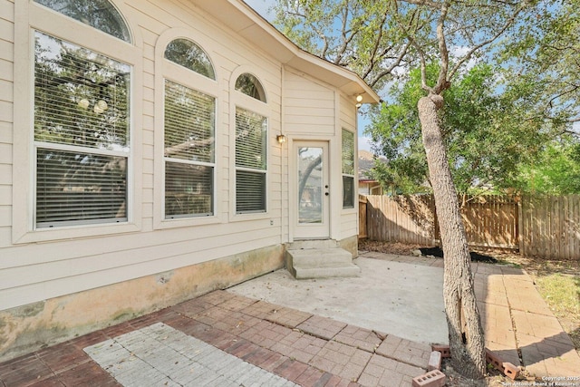 exterior space with entry steps, fence, and a patio