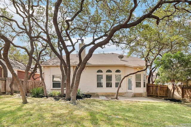 back of house featuring entry steps, a fenced backyard, a yard, and a chimney