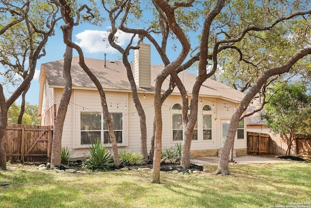 back of house with a patio area, a chimney, fence, and a lawn