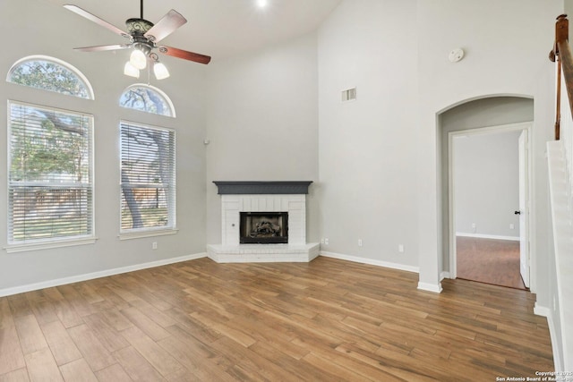 unfurnished living room with arched walkways, visible vents, a fireplace, and wood finished floors