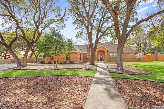 view of front of home with a front yard, fence, and brick siding