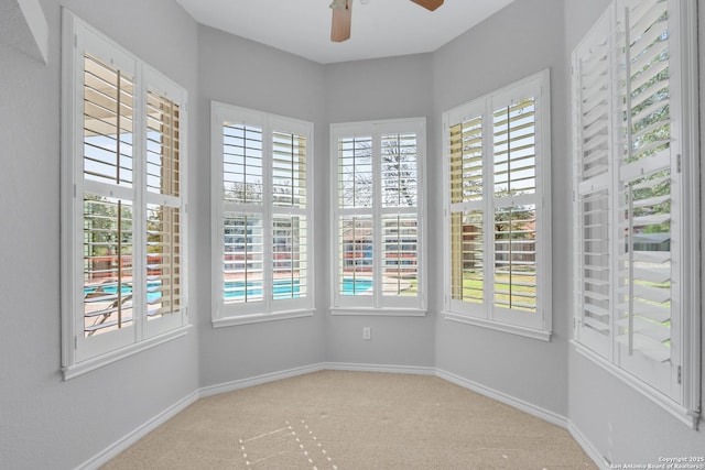 carpeted empty room featuring a wealth of natural light and baseboards