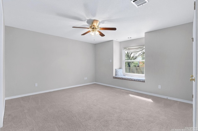 carpeted empty room with baseboards, visible vents, and a ceiling fan