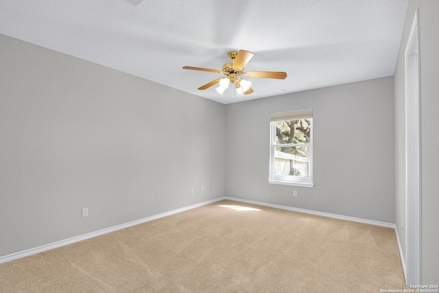 spare room with light carpet, a ceiling fan, and baseboards