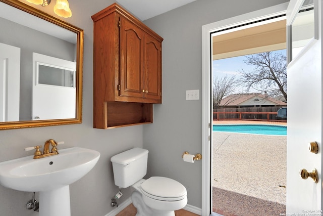 half bathroom featuring toilet, baseboards, and a sink