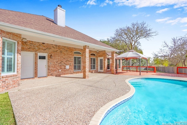 outdoor pool with a gazebo, a patio, and fence