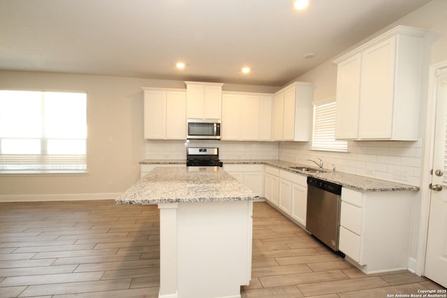 kitchen featuring white cabinets, wood finish floors, stainless steel appliances, and a center island