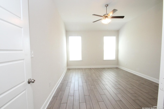 empty room featuring wood finished floors, a ceiling fan, and baseboards