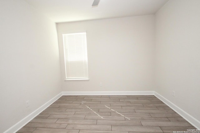 spare room featuring wood tiled floor, baseboards, and ceiling fan