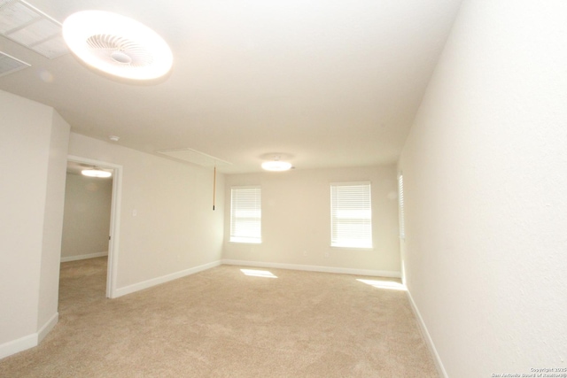 spare room featuring baseboards, attic access, and light colored carpet