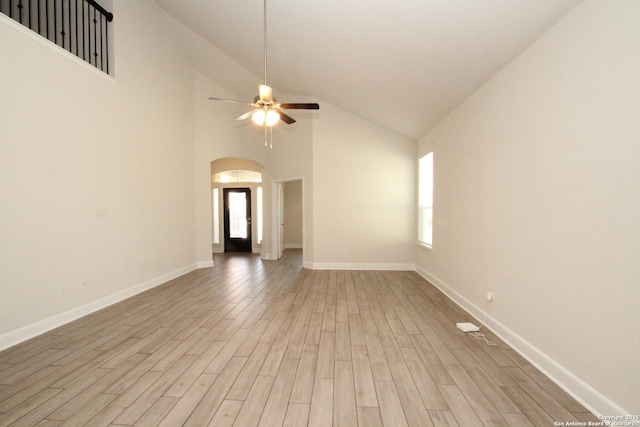 unfurnished room featuring light wood-type flooring, ceiling fan, arched walkways, and baseboards