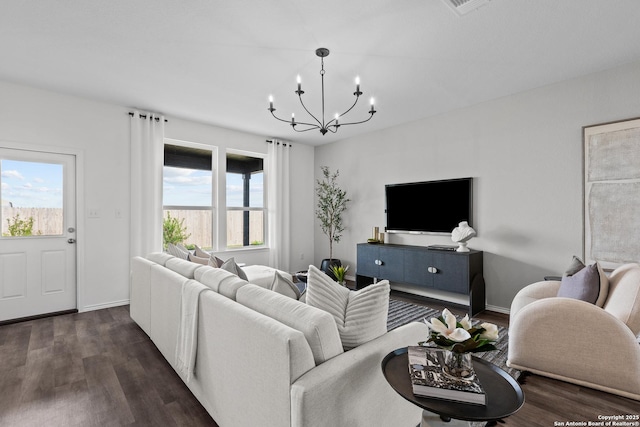 living area featuring a chandelier, dark wood-type flooring, and baseboards