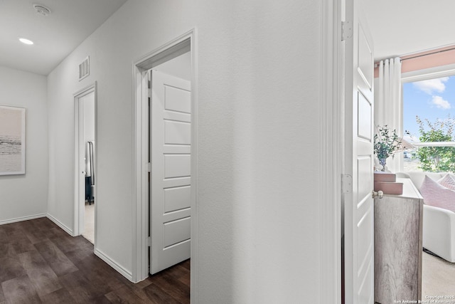 hallway with dark wood-style floors, visible vents, baseboards, and recessed lighting