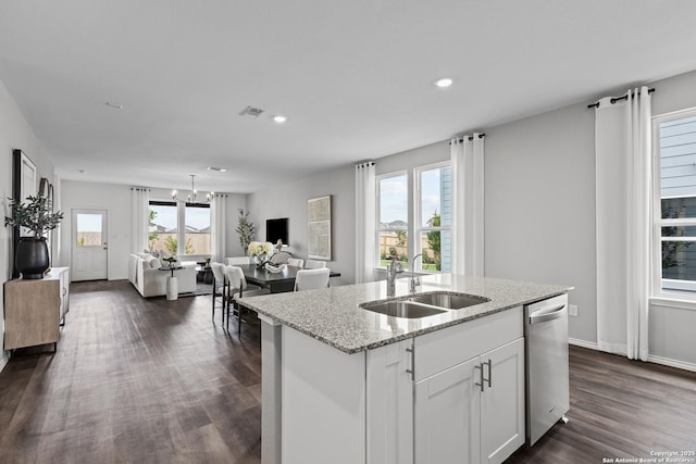 kitchen featuring visible vents, stainless steel dishwasher, open floor plan, a sink, and an island with sink