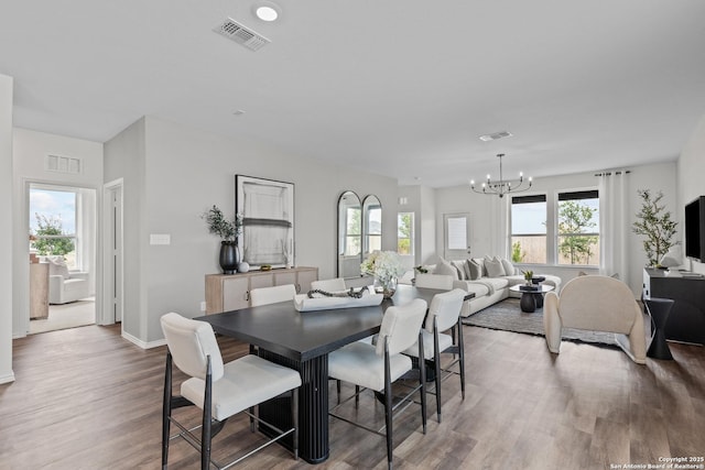 dining room featuring wood finished floors, visible vents, and an inviting chandelier