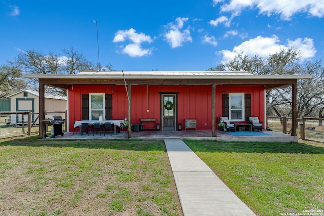 view of front of property with fence, an outdoor structure, board and batten siding, and a front yard