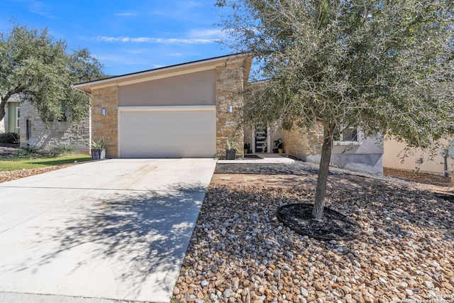 view of front of property featuring a garage, concrete driveway, stone siding, and stucco siding