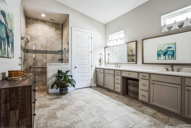 bathroom with a sink, double vanity, plenty of natural light, and a tile shower