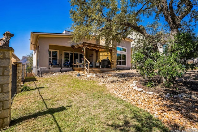 back of property featuring a yard and stucco siding