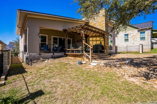 rear view of house featuring stucco siding, a lawn, metal roof, fence, and stone siding