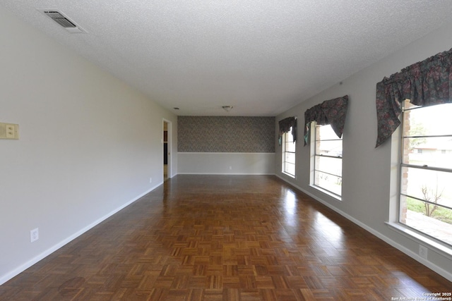 empty room with baseboards, visible vents, and a textured ceiling