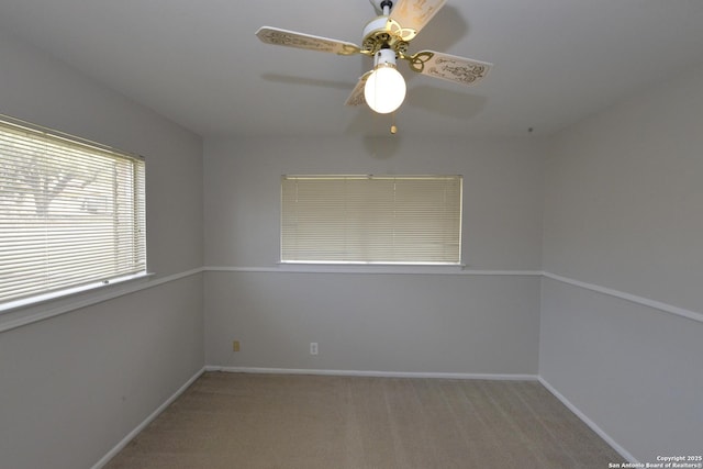 spare room with a ceiling fan, light carpet, and baseboards