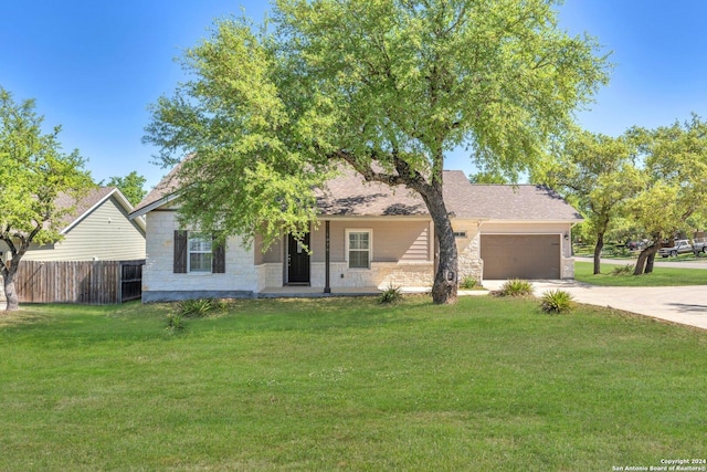 view of front of home with concrete driveway, an attached garage, a front yard, fence, and stone siding