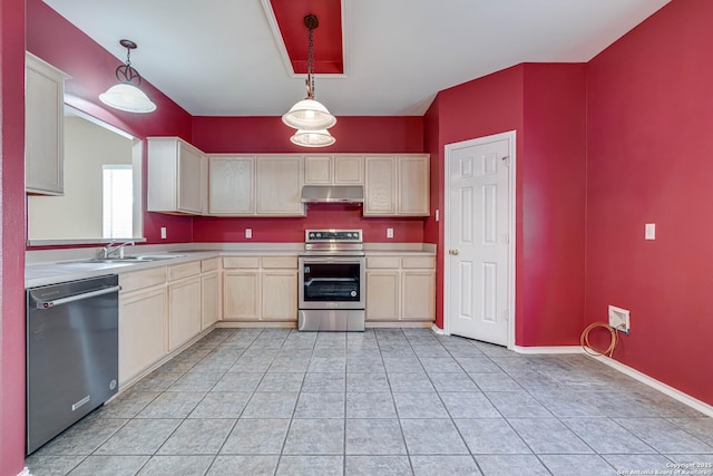 kitchen featuring stainless steel appliances, light countertops, under cabinet range hood, pendant lighting, and a sink