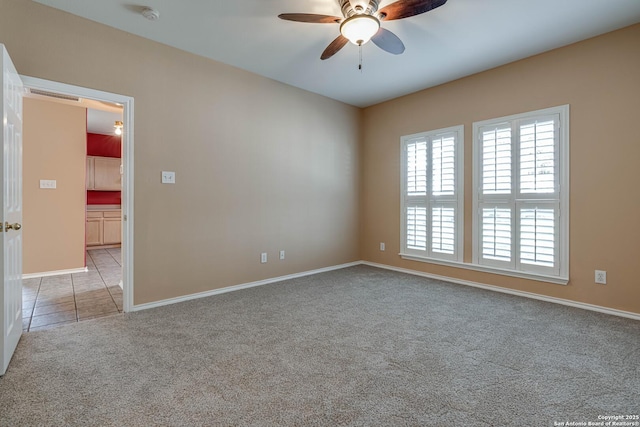 unfurnished room featuring ceiling fan, light tile patterned flooring, light colored carpet, visible vents, and baseboards