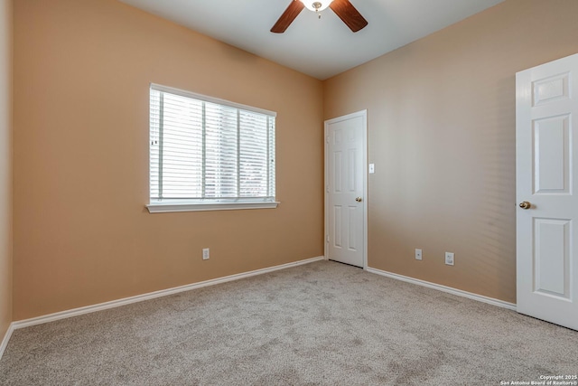 carpeted spare room featuring ceiling fan and baseboards