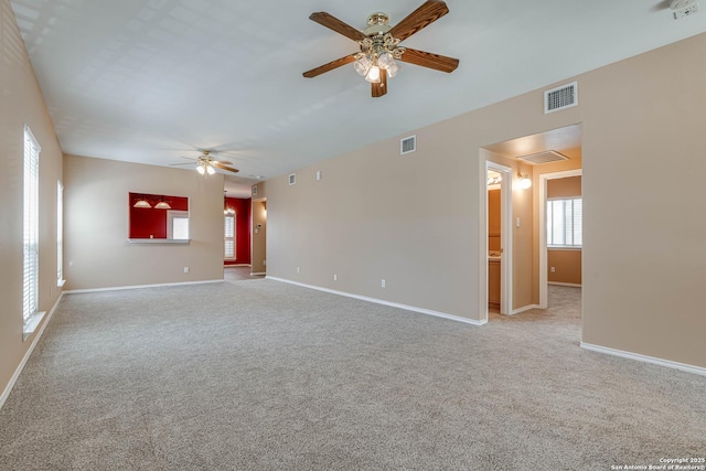 spare room featuring a ceiling fan, light colored carpet, visible vents, and baseboards