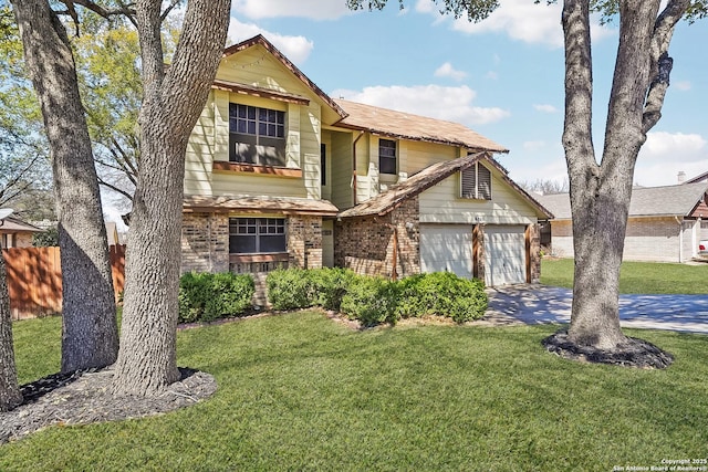 traditional home with brick siding, fence, a garage, driveway, and a front lawn