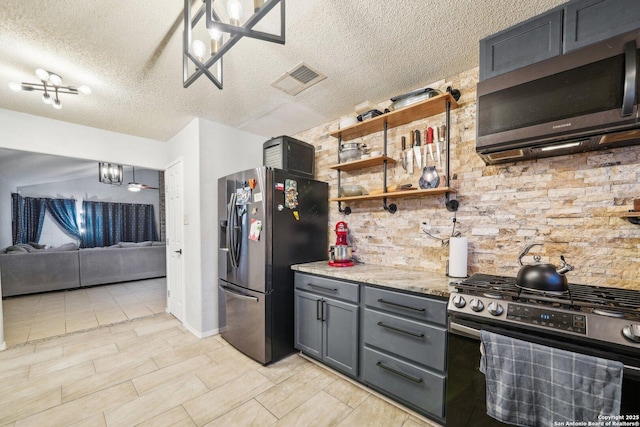 kitchen featuring stainless steel appliances, visible vents, gray cabinetry, open floor plan, and a textured ceiling