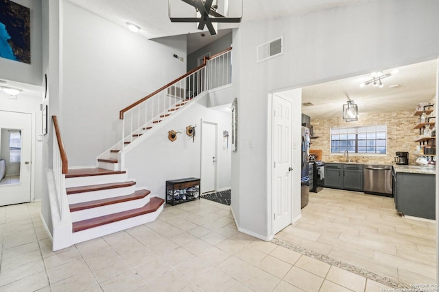 staircase featuring visible vents, a ceiling fan, tile patterned floors, a high ceiling, and a textured ceiling