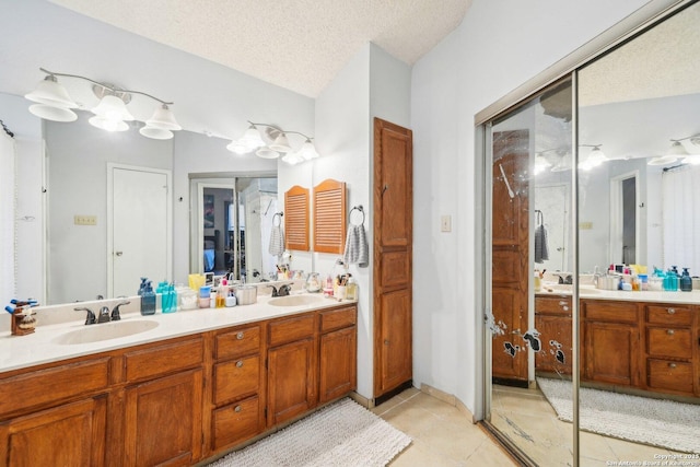 bathroom with tile patterned floors, a sink, a textured ceiling, and double vanity