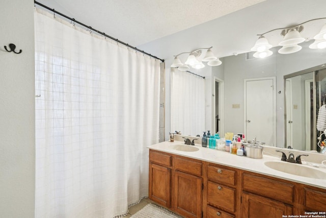 bathroom featuring a sink, a textured ceiling, a shower with shower curtain, and double vanity