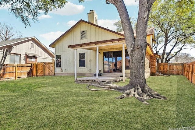 rear view of house with board and batten siding, a fenced backyard, a lawn, and a patio