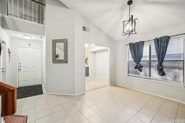 foyer entrance with light tile patterned flooring, visible vents, baseboards, vaulted ceiling, and an inviting chandelier