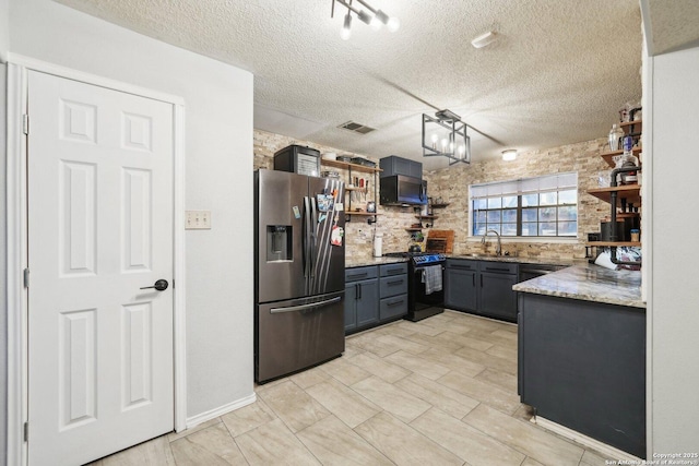 kitchen featuring black gas range, a sink, visible vents, stainless steel refrigerator with ice dispenser, and open shelves