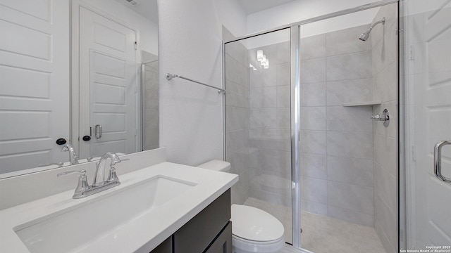 bathroom featuring toilet, a stall shower, and vanity