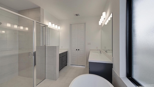 bathroom with a stall shower, vanity, tile patterned flooring, a soaking tub, and a closet