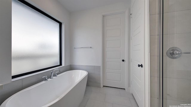 bathroom featuring a soaking tub, tiled shower, and tile patterned flooring