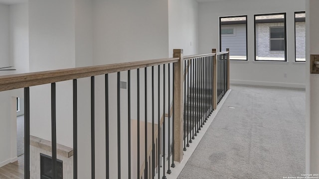 hall with baseboards, an upstairs landing, and light colored carpet