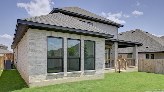 rear view of property featuring central air condition unit, a shingled roof, and brick siding