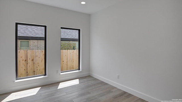 unfurnished room with wood finished floors, baseboards, and recessed lighting