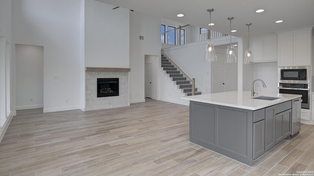 kitchen with appliances with stainless steel finishes, a sink, gray cabinets, open floor plan, and light countertops
